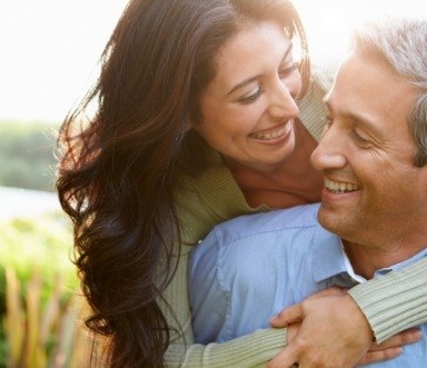 Man and woman with flawless smiles after all on four dental implant supported dentures
