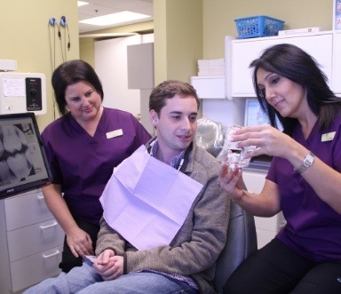 Dental team members and patients discussing what happens during a teeth cleaning