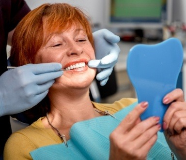 Woman looking at new smile after being fitted for a denture