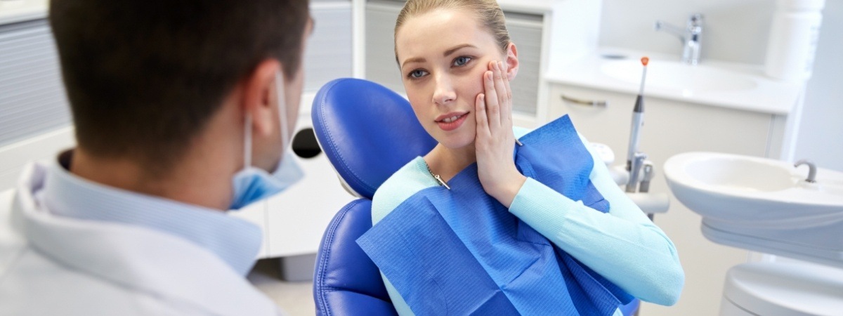 Woman holding cheek while visiting emergency dentist