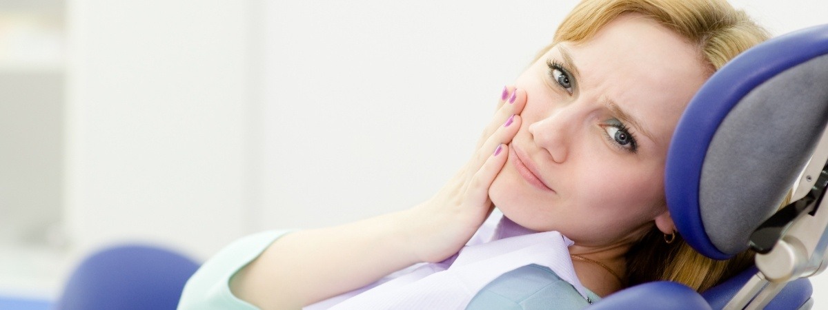 Woman in need of tooth extraction holding cheek in pain