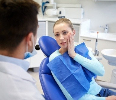 Woman at dental office holding cheek before tooth extraction