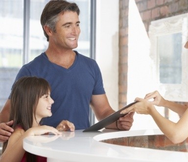 Father and child checking in at dental office for family friendly dental services