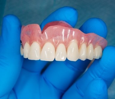 Hand holding full denture