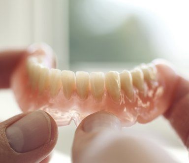 Hand holding a removable dental implant denture