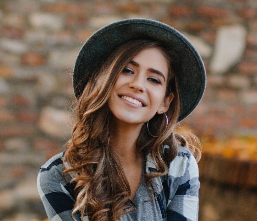 Young woman in a black and white plaid shirt smiling outdoors