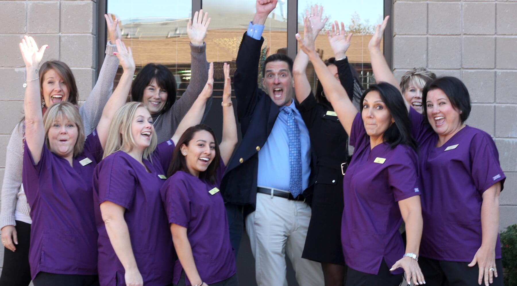 Burlington dentist and team members raising their hands