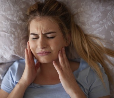 Woman holding jaw in pain due to bruxism