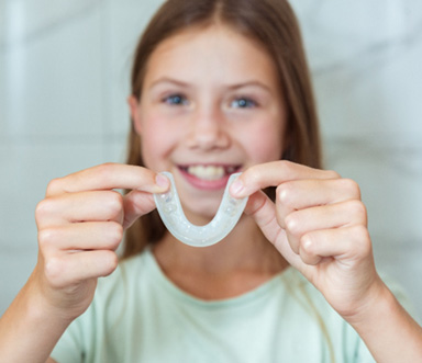 Young girl holding a custom mouthguard 