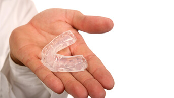 man holding clear mouthguard in hand