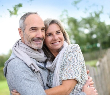 Older couple sharing healthy smiles after full mouth reconstruction