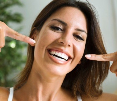 Woman pointing to smile after gum recontouring