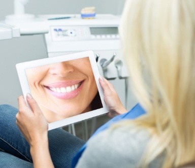 Woman looking at smile image after full mouth reconstruction