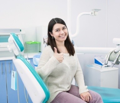 Woman smiling and giving thumbs up after root canal therapy recovery