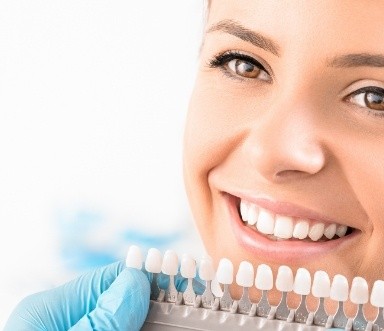 Bright smile compared to tooth shade chart after teeth whitening