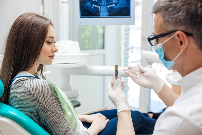 a dentist explaining the basics of dental implants in Burlington to a female patient