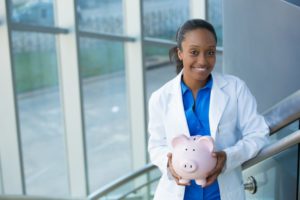 dentist in Burlington smiling and holding pink piggy bank 