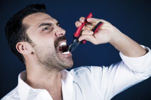 Man pulling his tooth with pliers instead of seeing his Burlington emergency dentist