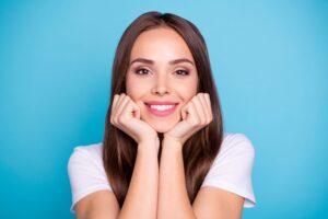 Woman with brown hair leaning on hands smiling