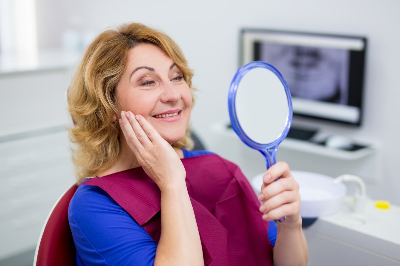 an older woman admiring her smile after a dental checkup in Burlington