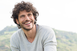 Man in light grey shirt outside smiling