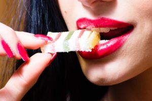 Woman eating a piece of candy.